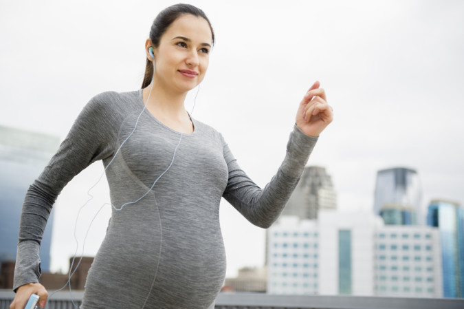 Pregnant Caucasian woman jogging on city street